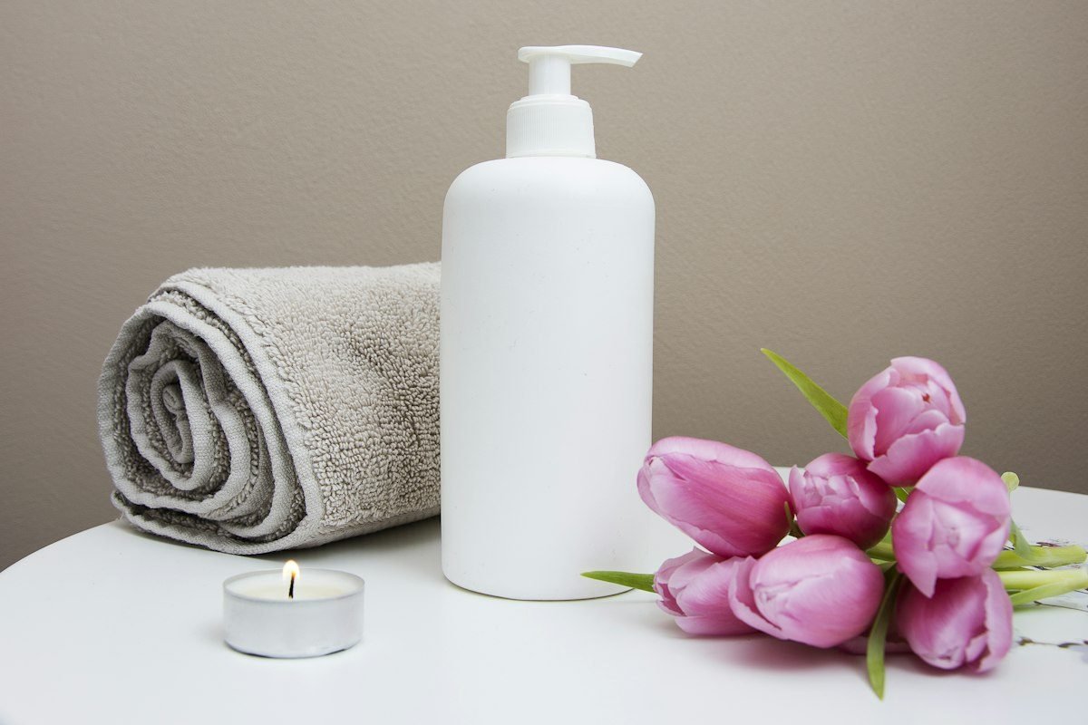 Rolled towel, lit candle, spa lotion and fresh tulips ready for a ritual at Bloom